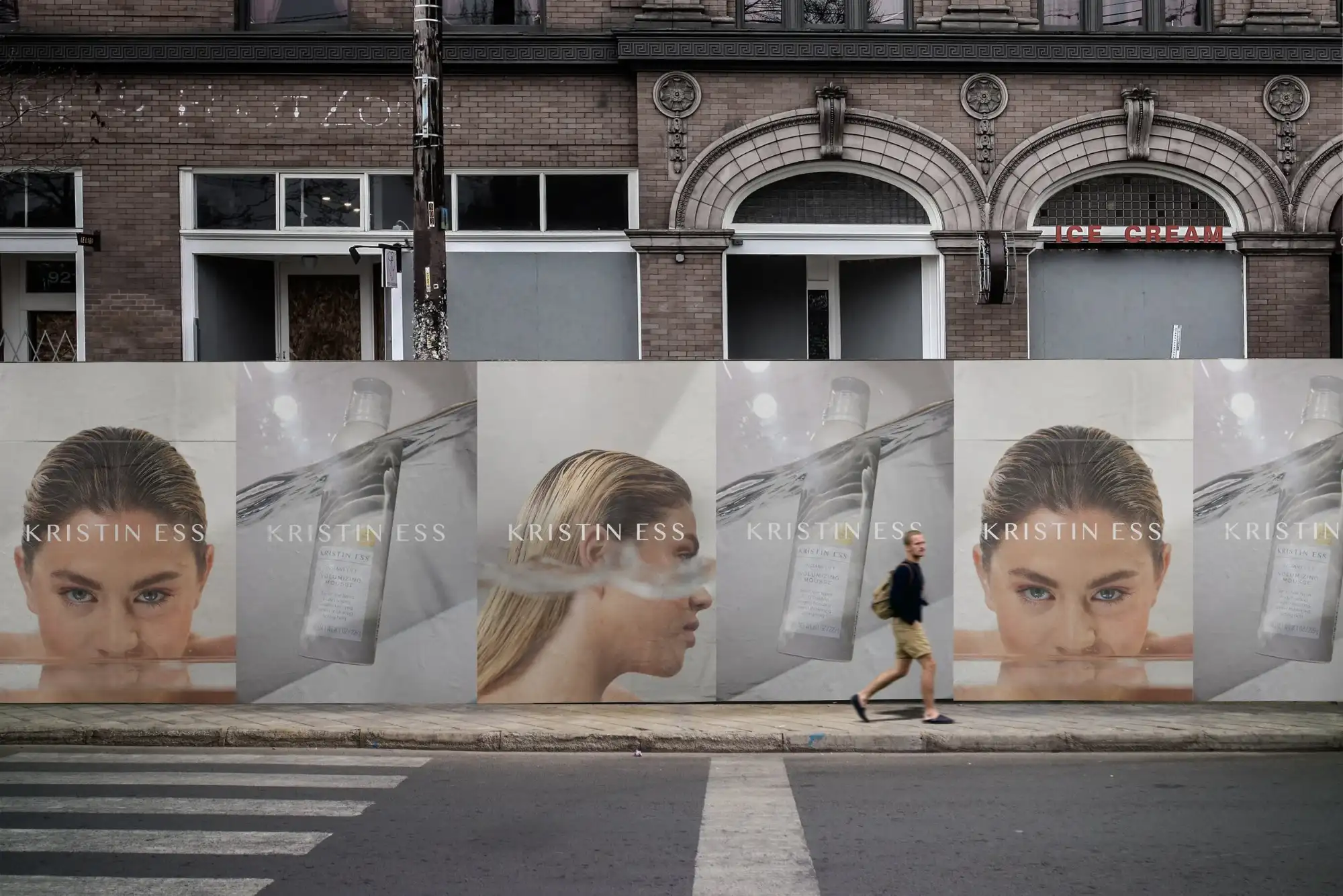 Row of Kristin Ess posters along a street hoarding