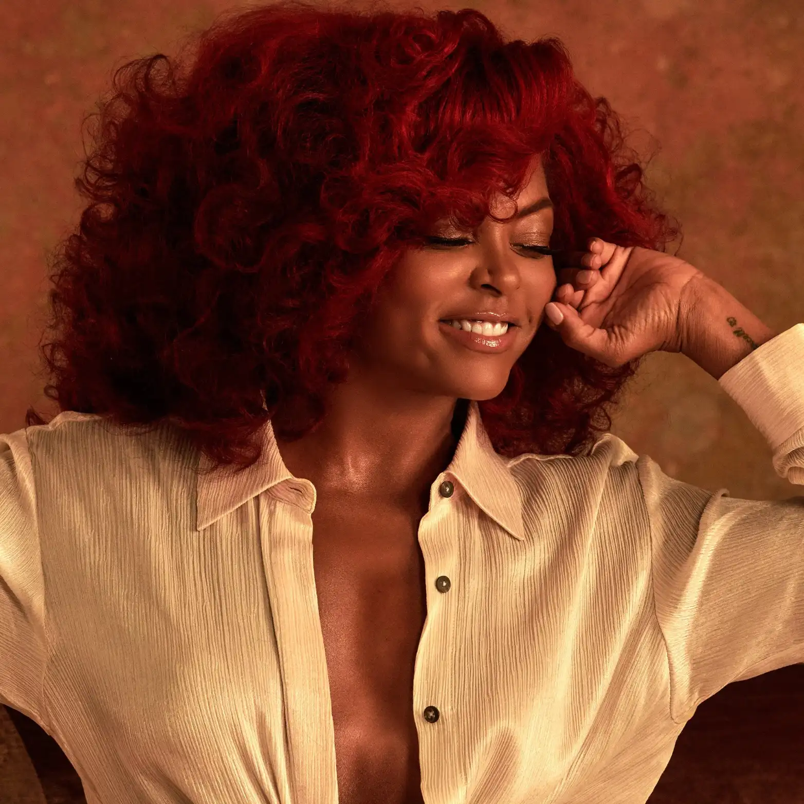 Model with voluminous red curls in a cream blouse