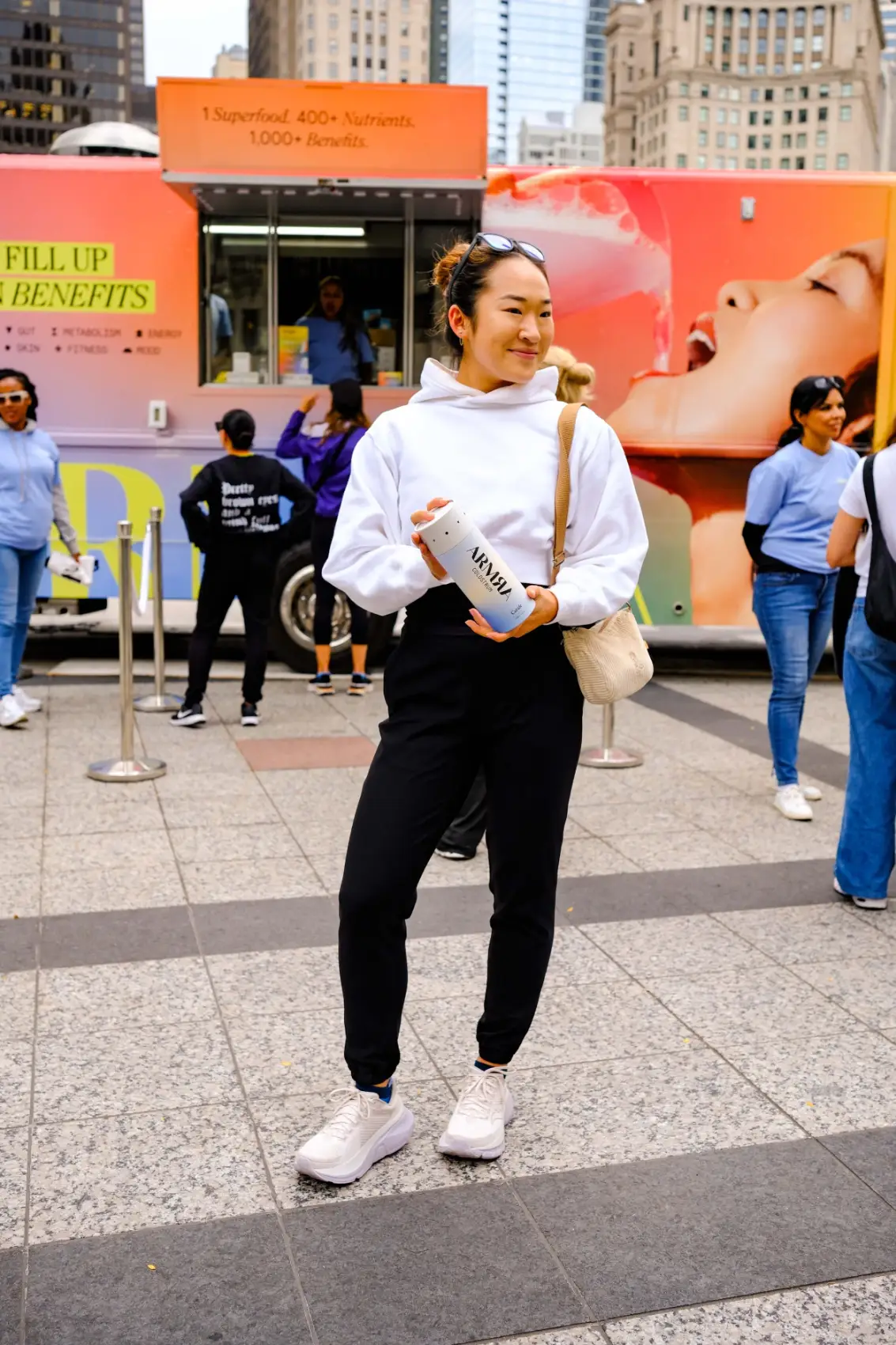 Visitor in a white hoodie holding a sample in front of the ARMRA truck