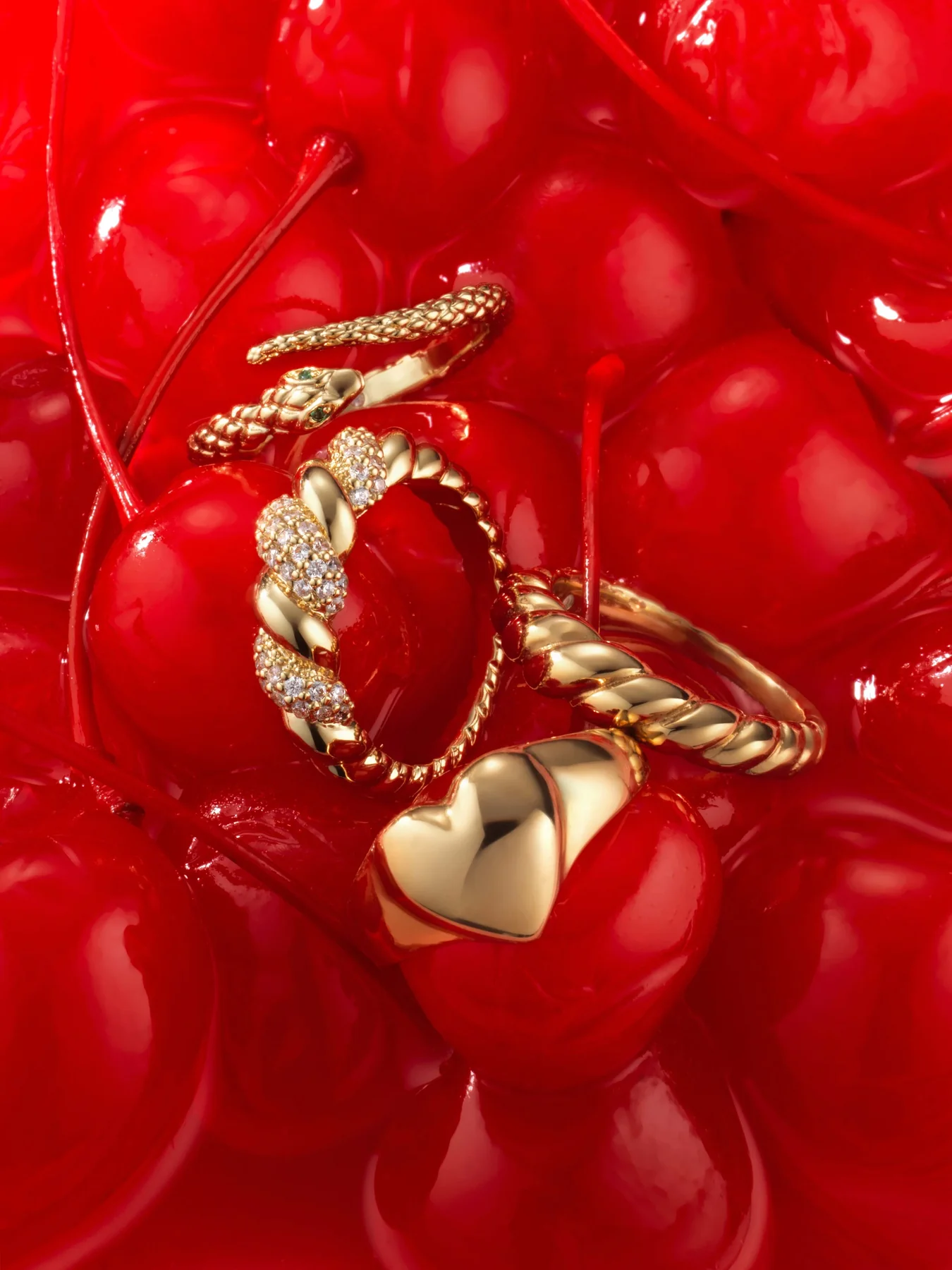 Gold rings and a heart ring on a pile of glossy red cherries