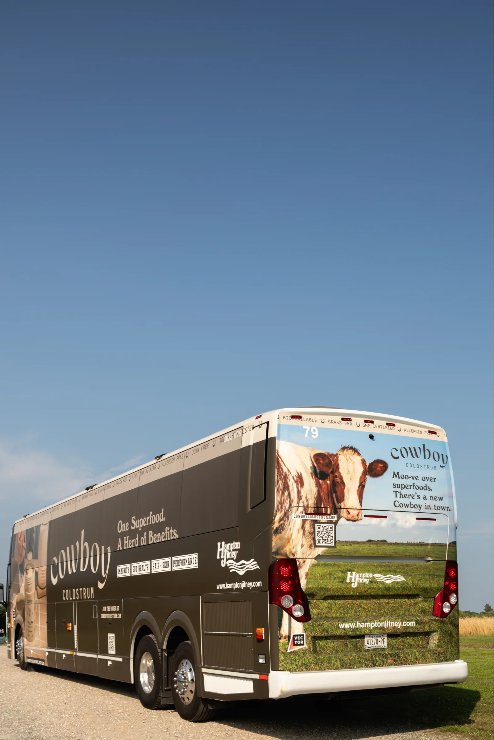 Rear of the wrapped coach under a deep blue sky: a cow and “Moo-ve over superfoods. There’s a new Cowboy in town.”