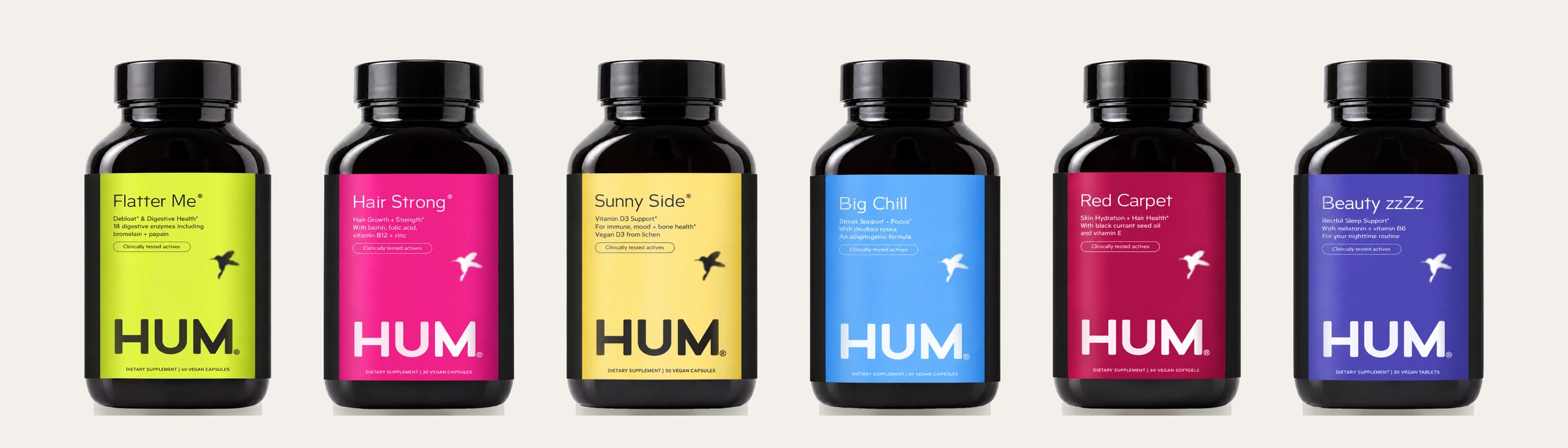 Six HUM bottles in a row with the new labels: Flatter Me in lime, Hair Strong in pink, Sunny Side in yellow, Big Chill in blue, Red Carpet in crimson and Beauty zzZz in violet