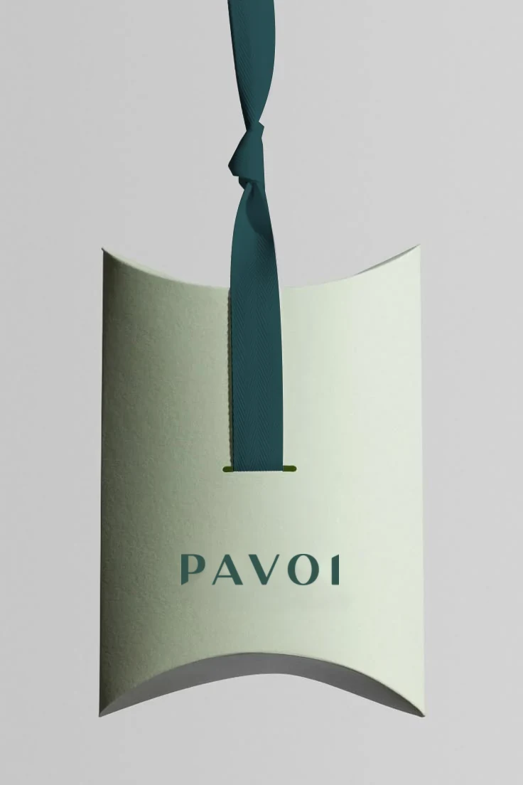 Sage PAVOI gift-with-purchase pillow box tied with a forest-green ribbon